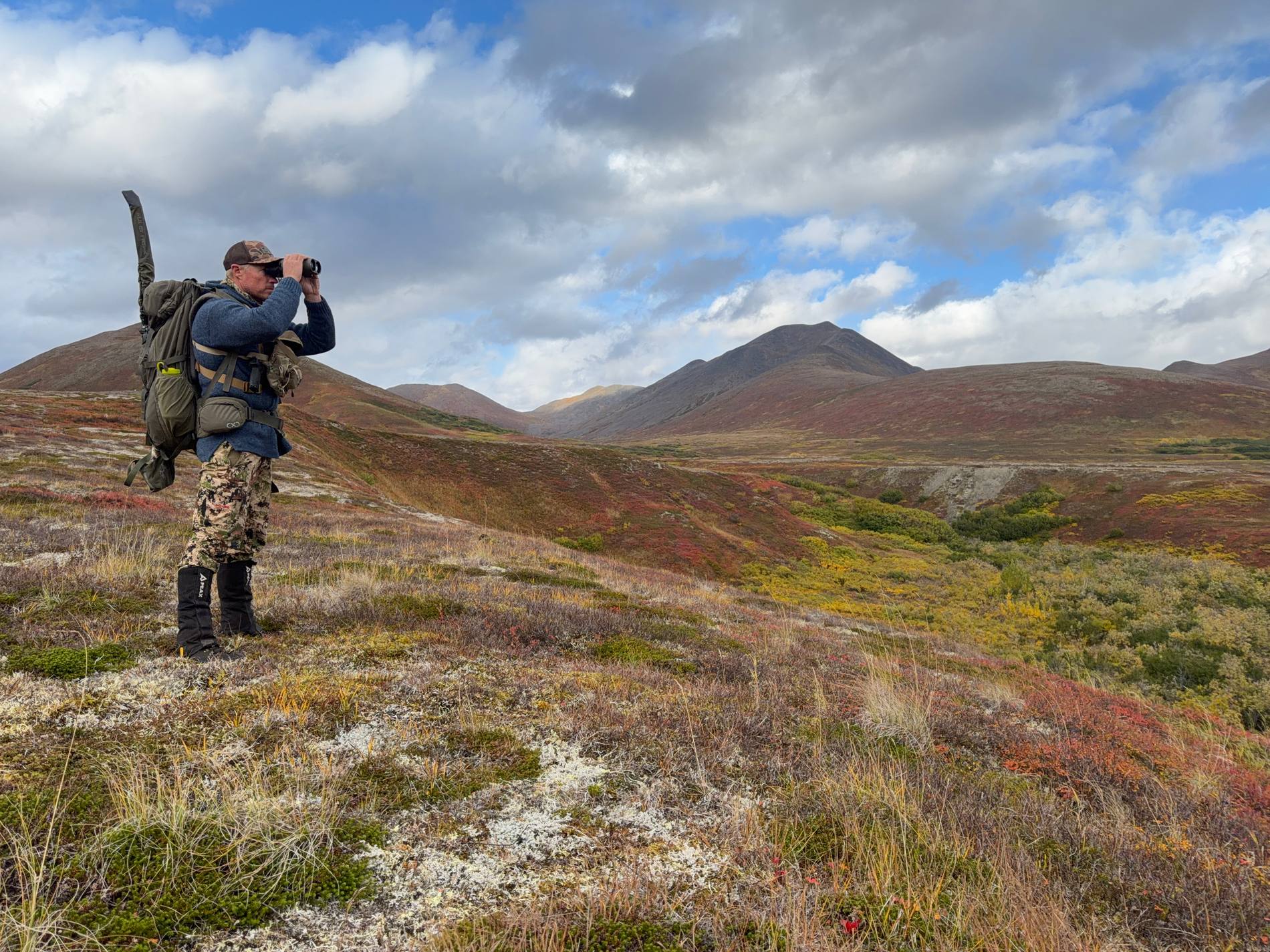 Hunter glassing red fall tundra in the backcountry