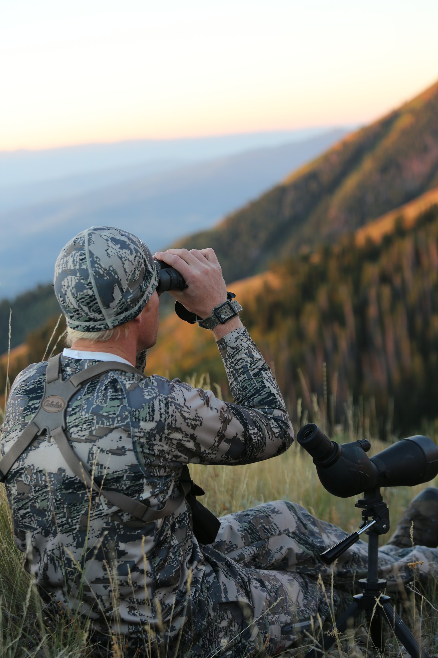 Tyce Erickson glassing a mountain basin with binoculars and a spotting scope