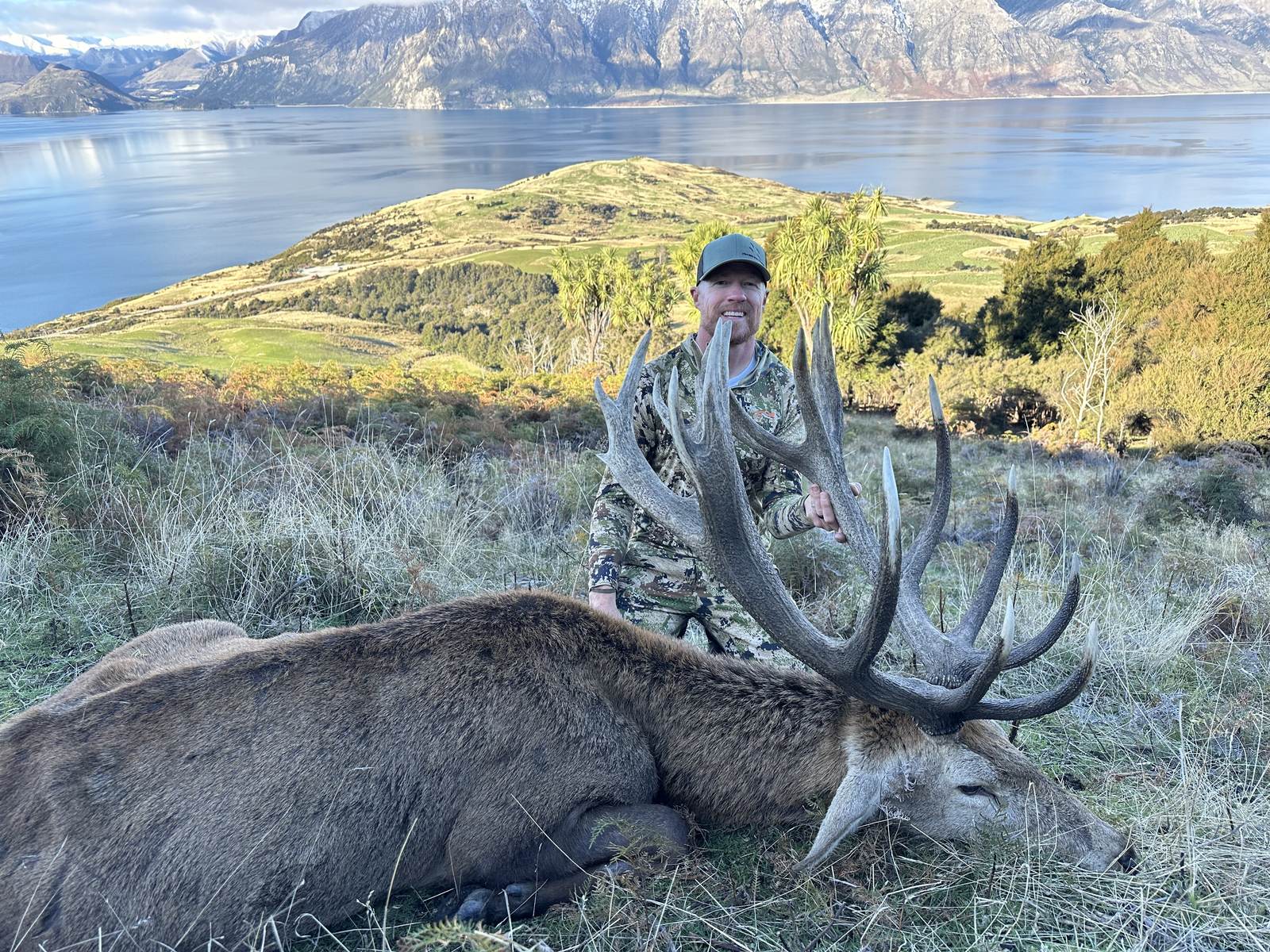 Tyce Erickson with a red stag above a mountain lake